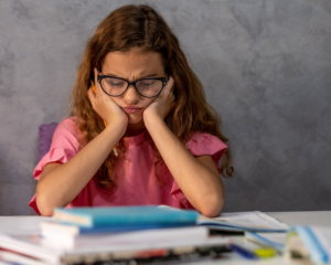 Schülerin sitzt frustriert am Tisch und kommt beim Lernen nicht weiter